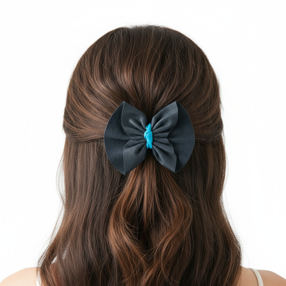 Model wearing navy and turquoise leather bow hair clip with white background